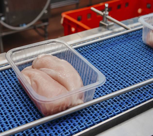 Production line with packaging and cutting of meat.Food products meat chicken in plastic packaging on the conveyor.Factory for the production of food from meat.Meat processing equipment.